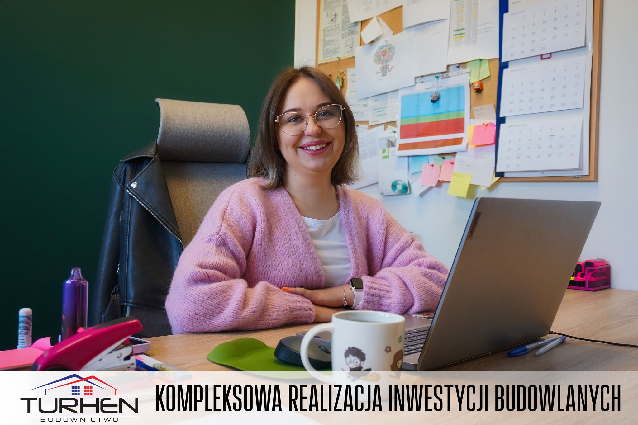 Pracownica Oliwia, uśmiechnięta siedzi przy biurku