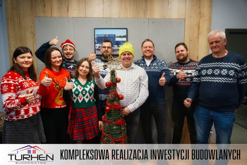 Ekipa Turhen Budownictwo wraz z Grinchem Henrykiem składa życzenia świąteczne Turhen Budownictwo na tle świątecznej dekoracji.